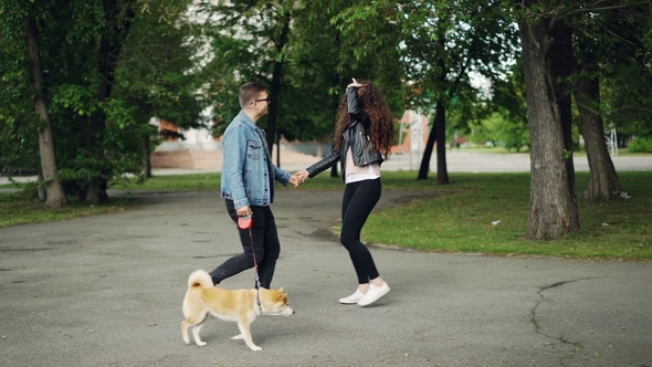 Pretty Young Woman Walking in the Park with Her Husband and Cute Small Dog