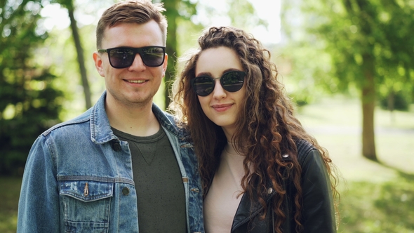 Portrait of Happy Couple Man and Woman Wearing Sunglasses and Trendy Clothing Looking at Camera and