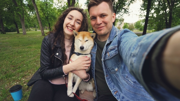 Point of View Shot of Two Happy People and Puppy Taking Selfie in the Park, Kissing and Loving