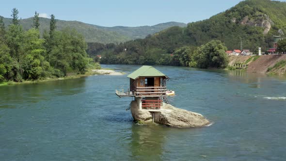 Drone Video in Which a Small House Stands on a Rock in the Middle of the River