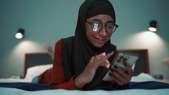 Handsome Arabian woman wearing eyeglasses typing on phone