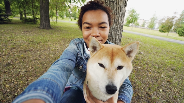 Point of View Shot of Pretty African American Girl Taking Selfie with Cute Puppy in City Park