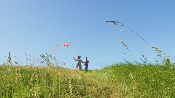 Children Run Down the Green Hill with a Flying Kite