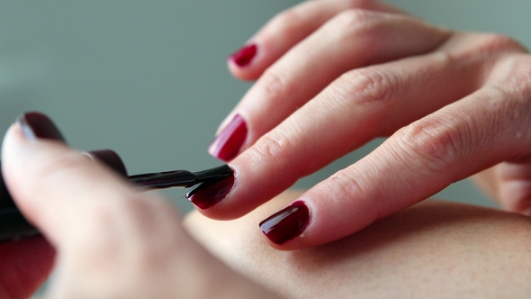 Manicurist Is Applying Claret Nail Varnish on Female Fingers.