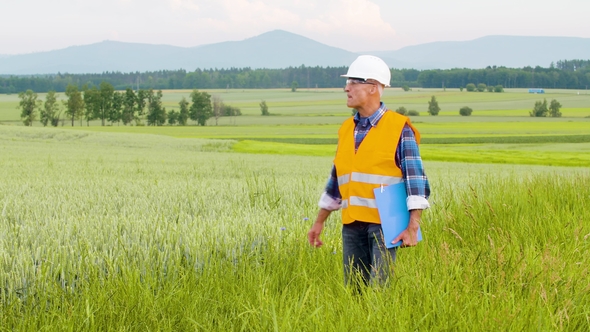 Engineer Analyzing Checklist On Clipboard Amidst Crops At Farm