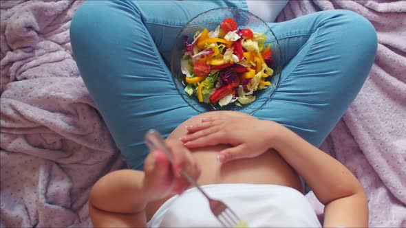 A Pregnant Woman Eats a Vegetable Salad Useful for the Unborn Child. Top View, a Pregnant Girl with