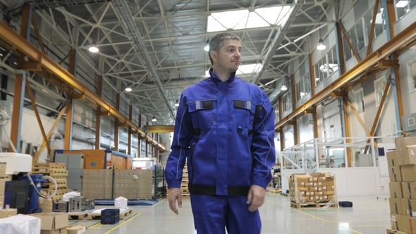 Engineer in in Blue Uniform Is Walking Through Factory