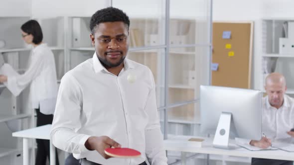 Black Colleague Practicing Ping-Pong in Office
