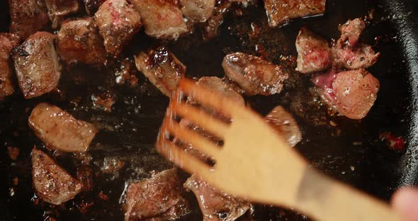 A Wooden Spatula Stirs the Fried Liver in Oil. 