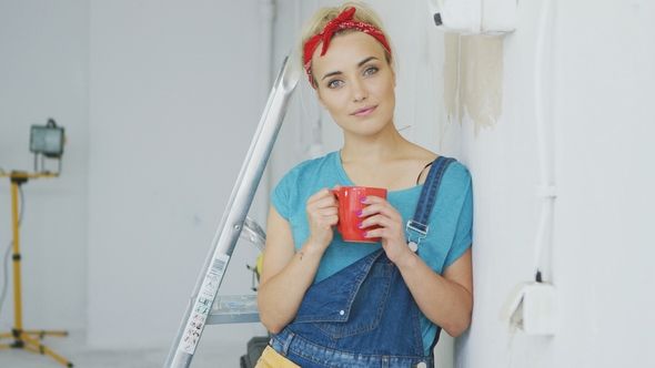 Smiling Female in Overalls Leaning on Wall