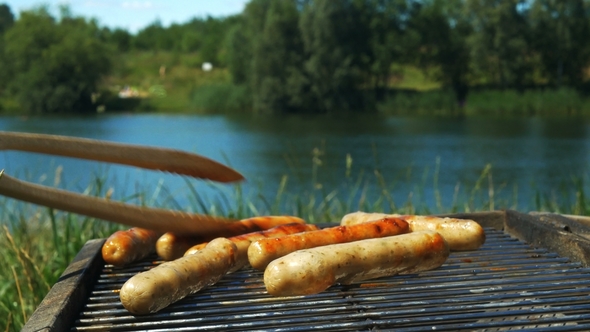 Grilling Sausages on a Sunny Summer Day in Front of a Lake