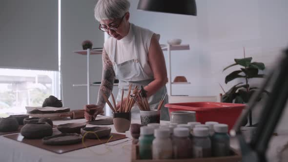 Asian elderly woman enjoying pottery work at home.