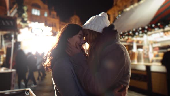 Two Girls Young Lesbian Women Embrace on the Square in the Lights of the Fair on Christmas