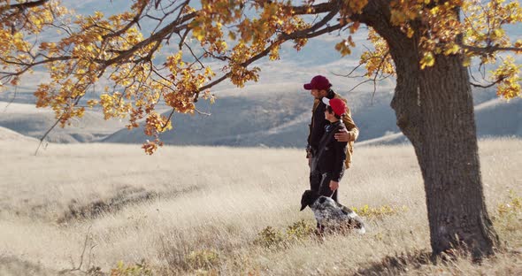 Father and Son with Dog Walk in Autumn Nature and Enjoy Companionship