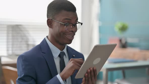 Young African Businessman Celebrating Success on Tablet