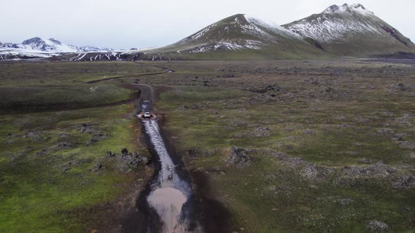 Aerial of a Car Driving Through the Puddle on a Mud Dirt Road in Iceland