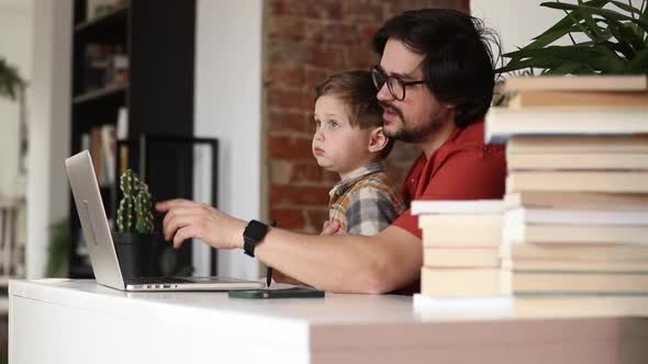father with a son at working place in home office