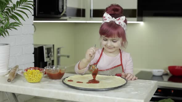 Cooking Pizza. Little Child in Apron Adding Tomato Sauce To Dough in Kitchen