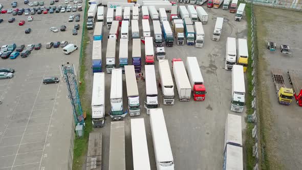 Shooting from a drone to a truck parking lot. Many trucks are parked at port,