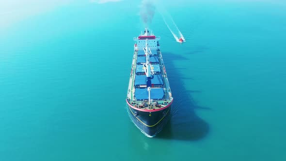 AERIAL VIEW: Flying Over Massive Ship Filled Moving in the Quiet Sea. Cargo Being Moved By Large