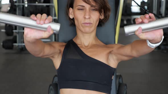 Sporty Woman is Making Exercises for Arms Muscles on Training Machine