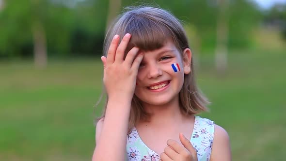 Adorable Little Girl Smile at Camera with Cheeks Painted in Flag of France