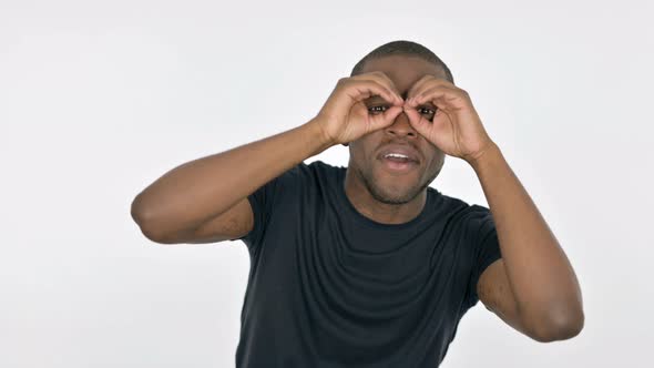 Searching Young African Man with Binocular Gesture on White Background