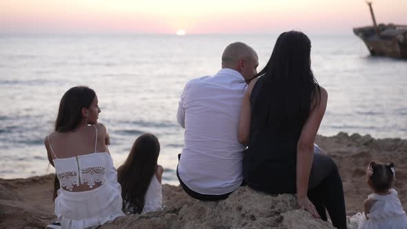 Back View of Caucasian Carefree Family Admiring Sunset on Mediterranean Sea Coast Talking