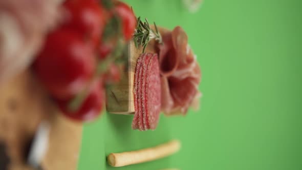 Vertical video, Close-up: cold cuts, salami, prosciutto, jamon, cherry tomatoes, sliced ​​sausage