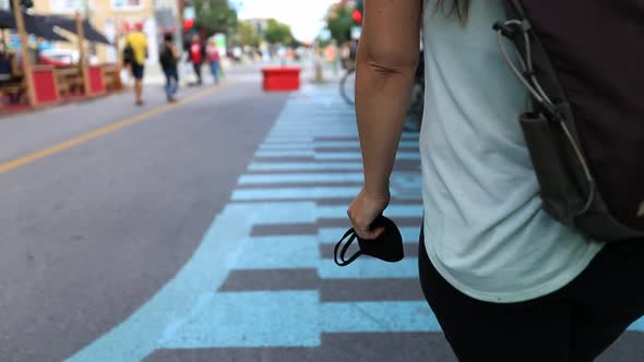 Woman Holding Mask in Hand Walking