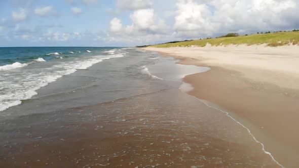 AERIAL: Flying Backwards and Revealing Golden Sand Beach on a Sunny Day