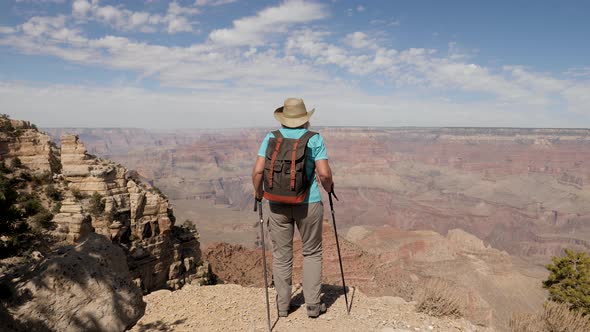 Hiker Woman Walks The Edge Of Grand Canyon Cliff And Raises Her Hands Up Success