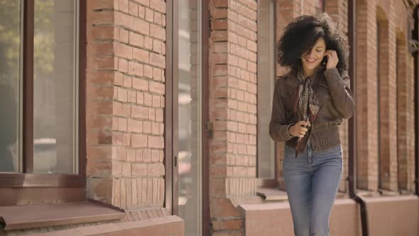 Happy Young African American Woman Walking Down Street and Dancing Cheerfully