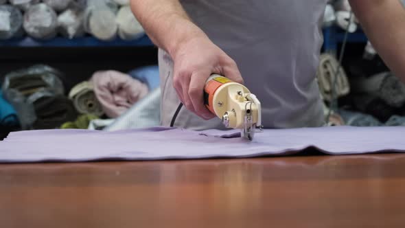 Male Worker Using Electric Cutting Fabric Machine