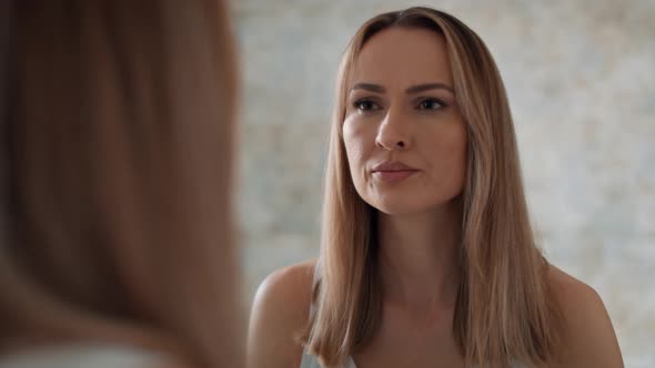 Serious woman standing in front of bathroom mirror and looking at herself. Shot with RED helium came