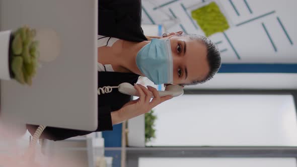 Vertical Video Entrepreneur with Protective Face Mask Discussing on Landline