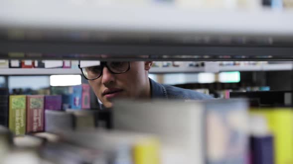 College Library. Male Student Searching For Book On Bookshelves