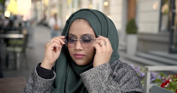 Muslim Woman in a Hijab with Poor Eyesight Puts on Glasses