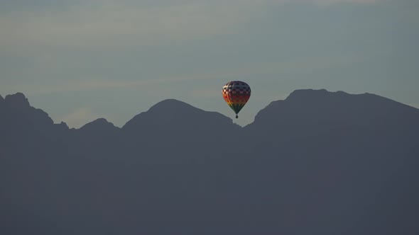 Balloon Flying Along the Mountains. Mountains in Shadow in the Background. The Balloon Flies