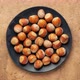 Hazelnuts in shells are falling onto a black ceramic plate - stop motion - VideoHive Item for Sale