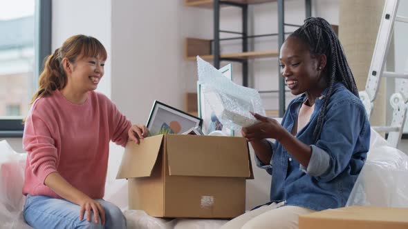 Women Moving to New Home and Unpacking Boxes