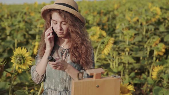 Happy Lady Speaking on the Mobile Phone Among Beautiful Summer Sunflowers