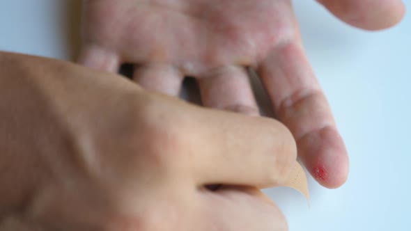 Male Applying Band Aid Patch to Injured Sore Fingers