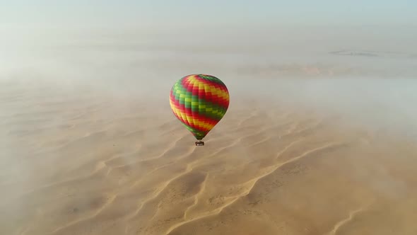 Aerial view of hot-air-balloon flying in the clouds on desert in Dubai, U.A.E.