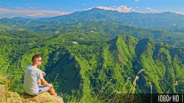 Rear View of Man sitting on Rock Cliff Admiring Beautiful Valley & Natural Landscape of Sri Lanka