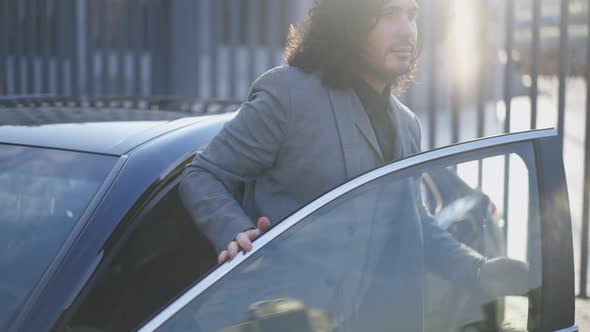 Successful Serious Businessman Walking Out Car Closing Door and Looking at Camera