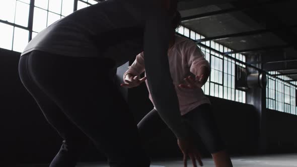 African american man and woman standing in an empty building playing basketball