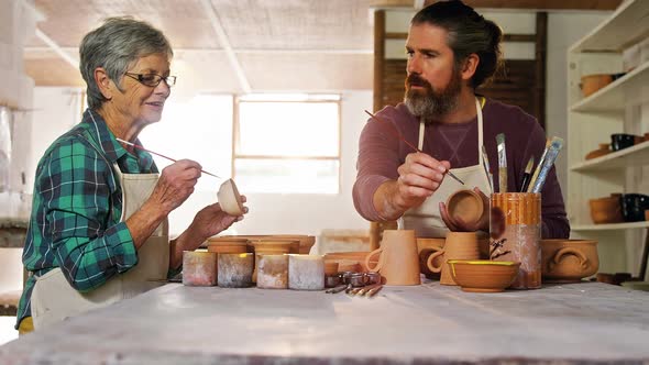 Male and female potter painting pots