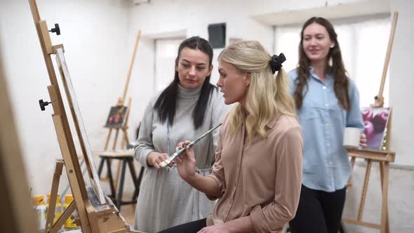 Women discussing painting during workshop in art studio