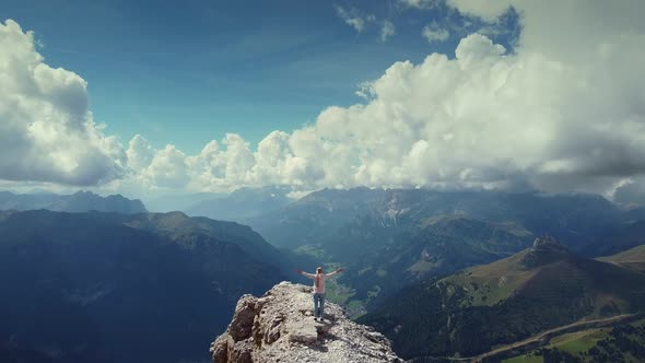 Flying Over Woman with Raised Hands Standing on Piz Boe Mountain Top in Dolomites